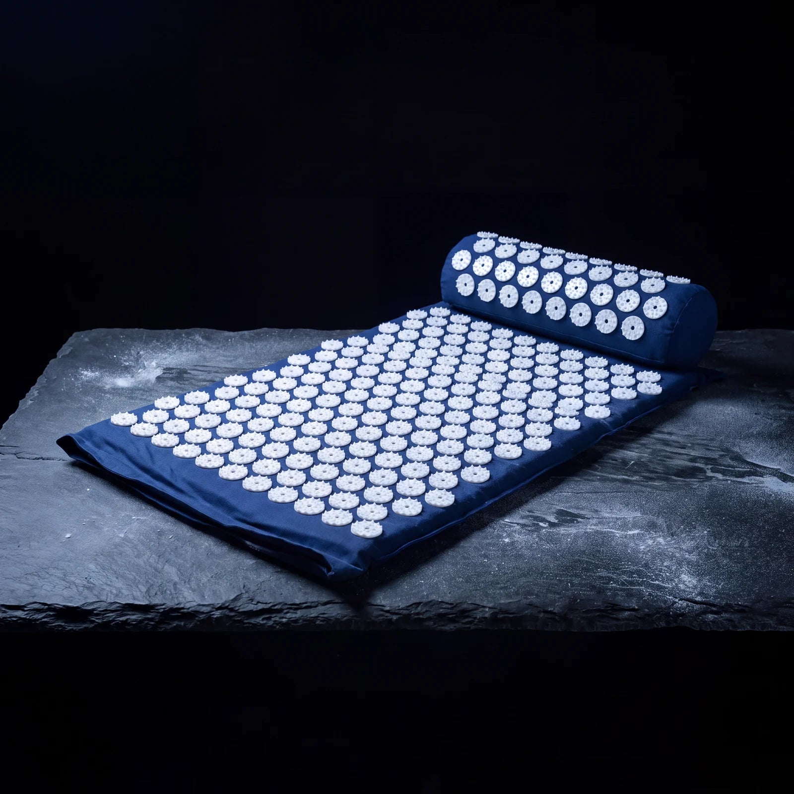 Navy acupressure mat and pillow on a slate shelf