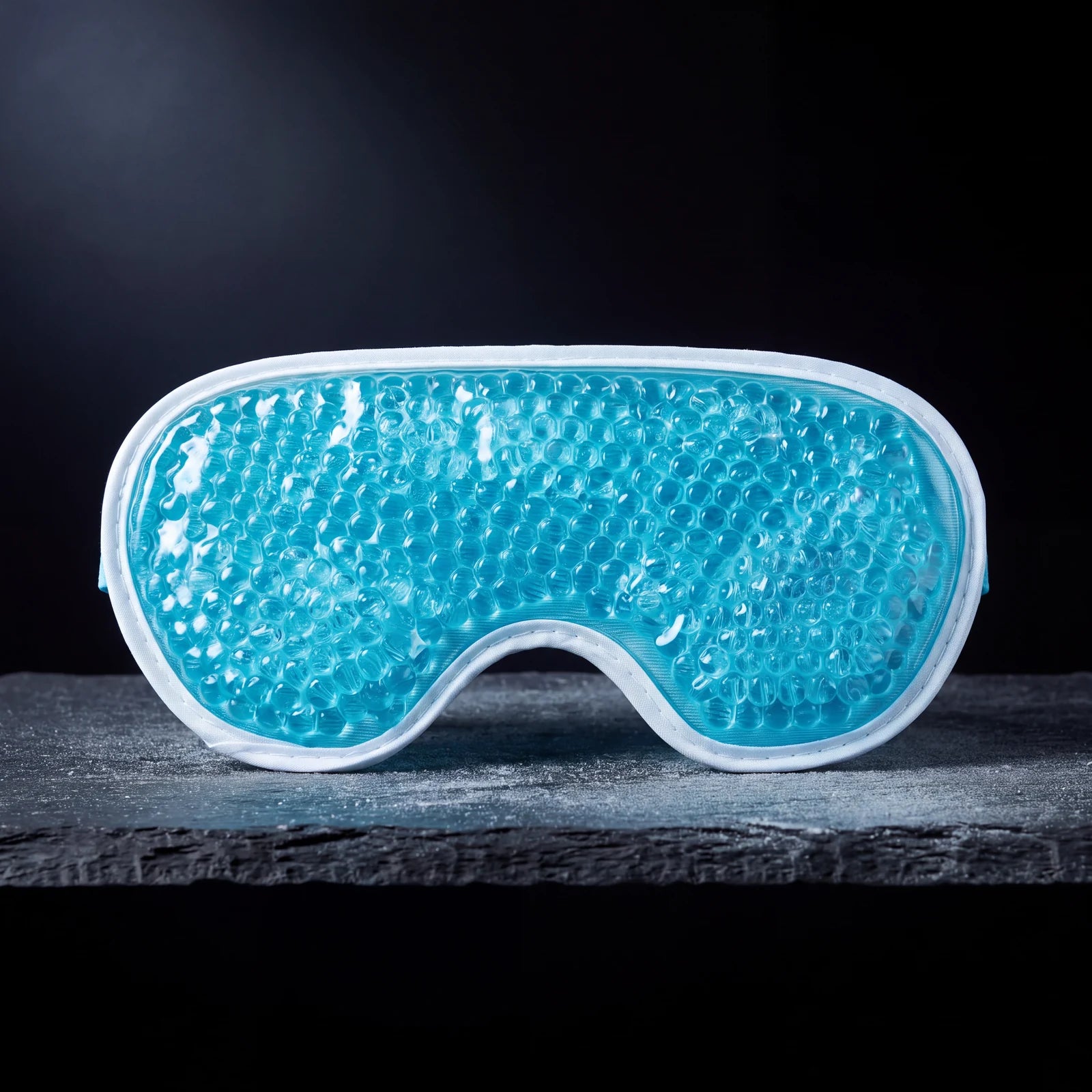 Teal gel-bead cooling eye mask on a slate shelf